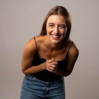 Thumbnail for Laughing woman wearing a black top and jeans, exuding joy and warmth, showcasing a cheerful demeanor.