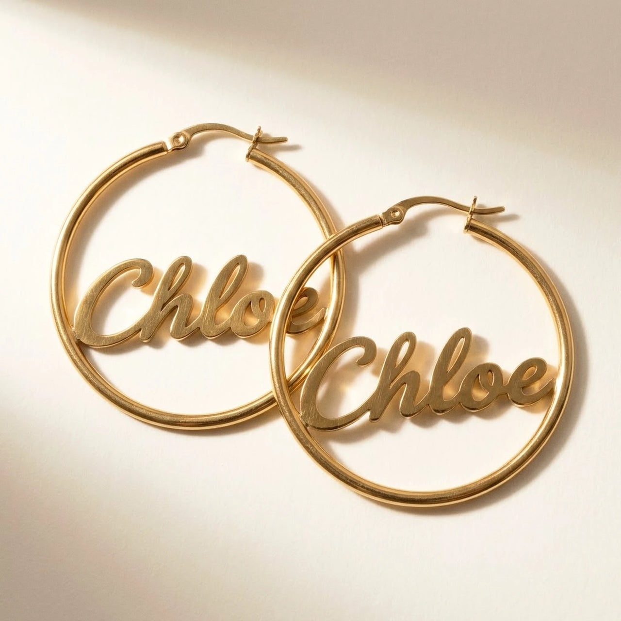 Custom Name Hoop Earrings in Gold, studio packshot of the pair on a plain background | SKU: name-hoop-gold-30-mm
