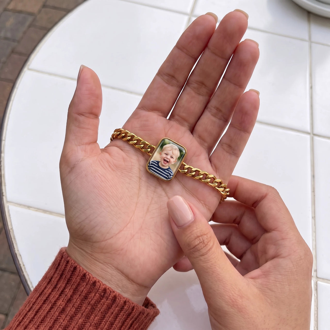 Thumb warming the gold cushion bracelet plate: the hidden photo appears under the thumb while the rest stays black | SKU: TPH-CUSB-GOLD