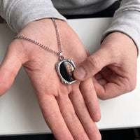 Thumbnail for Thumb warming the silver oval pendant: the hidden photo appears under the thumb while the rest stays black | SKU: TPH-OVLN-SILVER